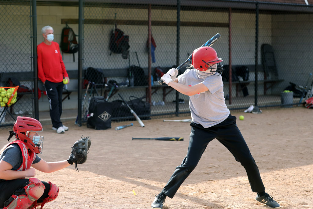 The 2020-21 season is unlike any of the 36 campaigns that preceded it for Central’s NFCA Hall of Fame Coach George Wares ’76, who watches a masked Taryn Hintz ’24 take a cut in a small-group fall practice.