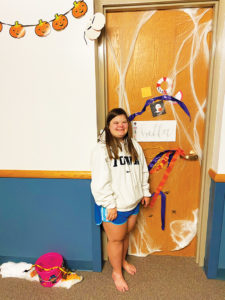Bella posing near her dorm room door, which she decorated for Halloween 2020.