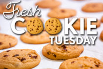 Text that reads, "Fresh Cookie Tuesday," over a background photo of fresh chocolate chip cookies.