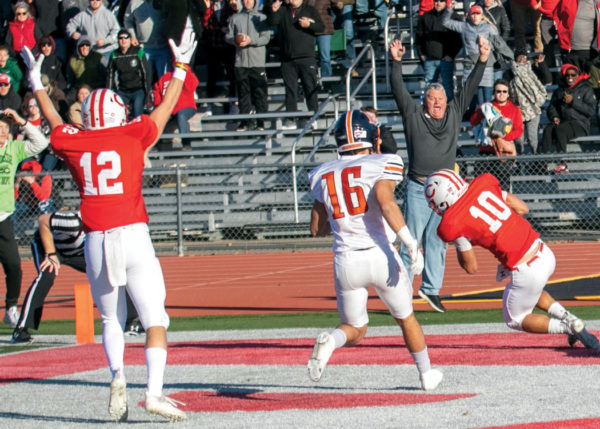 Wide receiver Hayden Vroom ’22 (No. 12, left) and Don De Waard ’82 (right) simultaneously give the touchdown signal in the end zone as Tanner Schminke ’21 (No. 10) cradles the winning touchdown pass as time expired in Central’s 30-28 NCAA Division III playoff win over Wheaton College (Ill.) Nov. 27